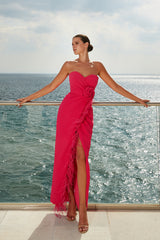 femme dans une robe rose debout sur un balcon surplombant l’océan, robe bustier, longue robe fluide luxueuse