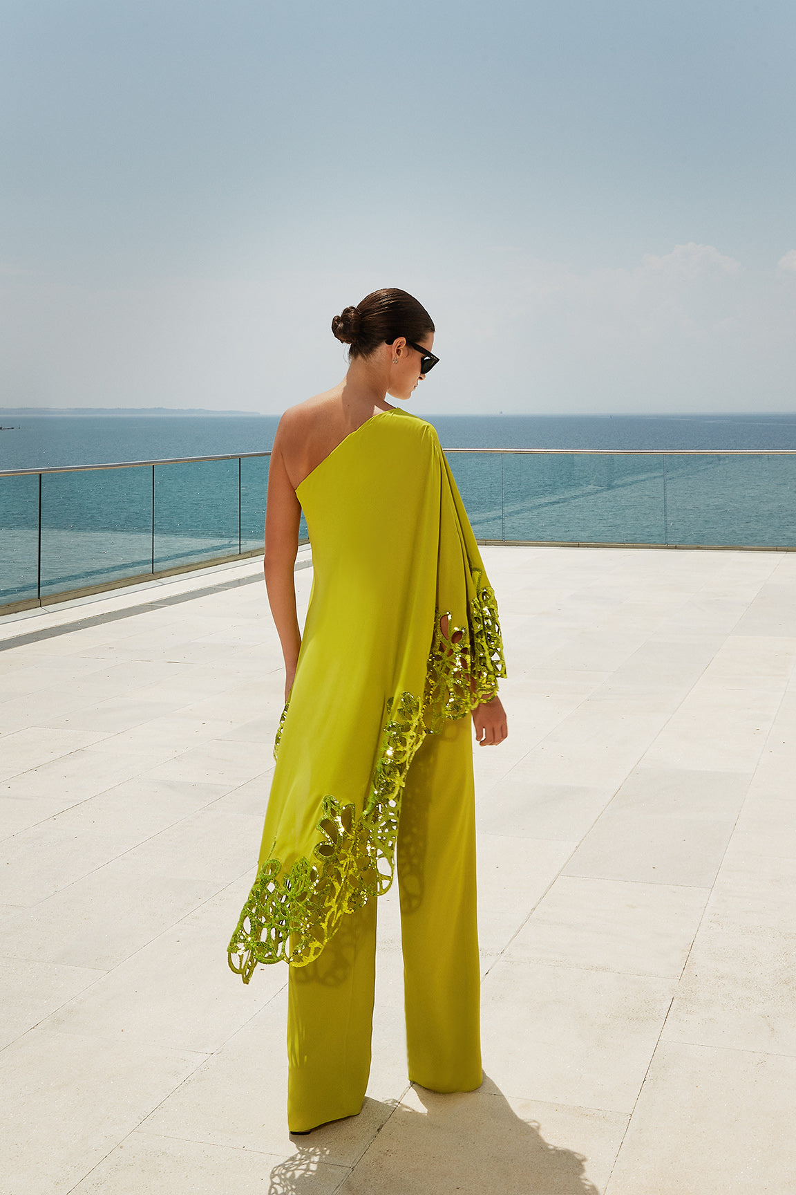 Vêtu d’une robe jaune et d’une écharpe jaune debout sur un patio, une salopette jaune, teinte citron vert et or, près de la mer