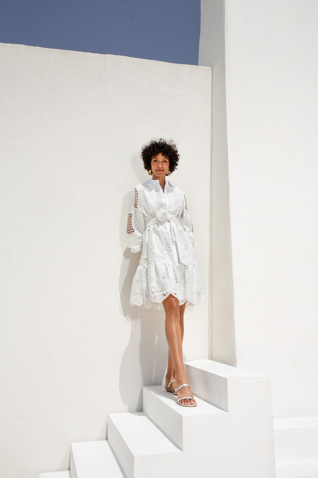 une femme debout sur un escalier dans une robe blanche, robe polygonale blanche