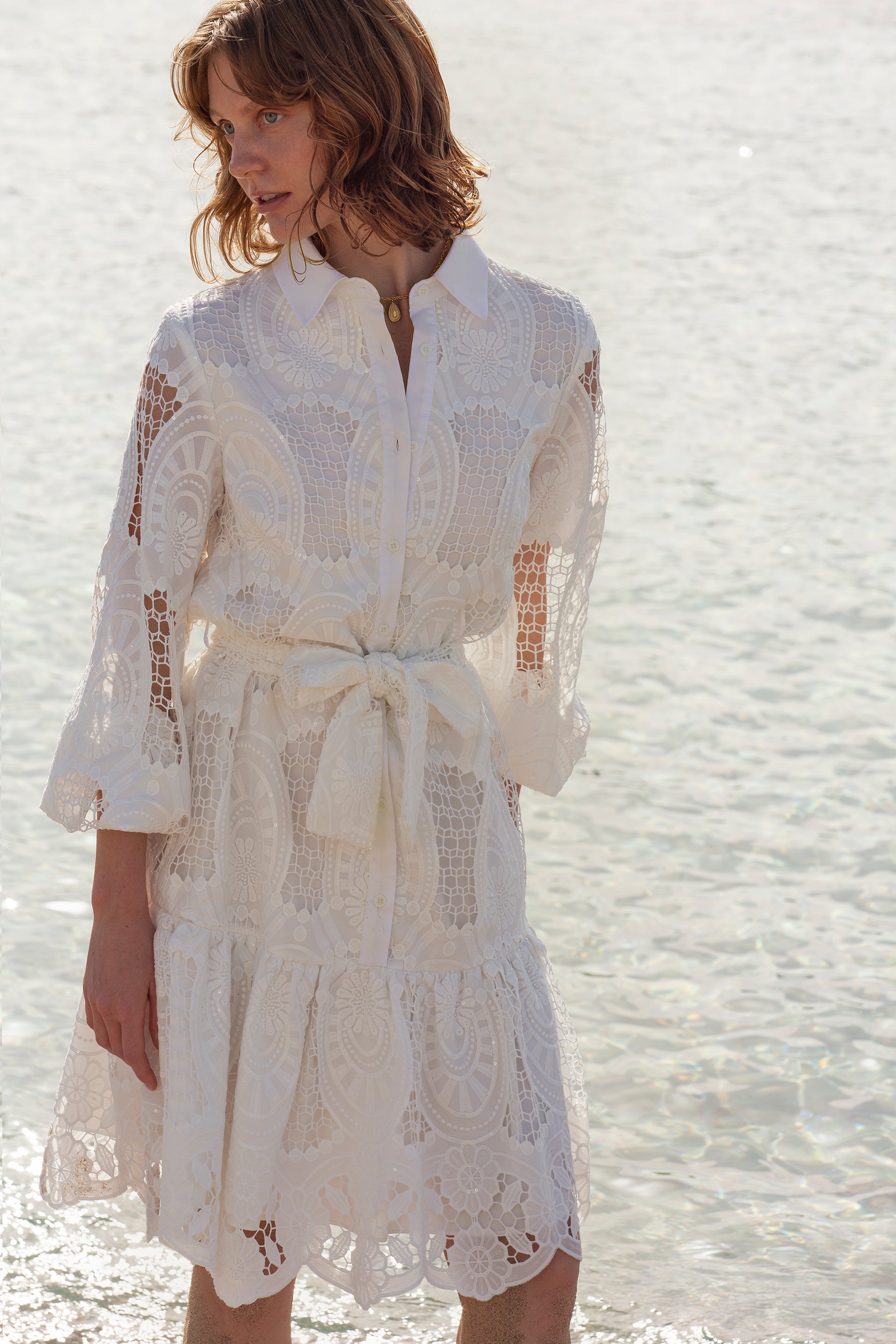 femme en robe blanche debout sur la plage près de l’eau, robe en dentelle blanche, vêtements en dentelle blanche